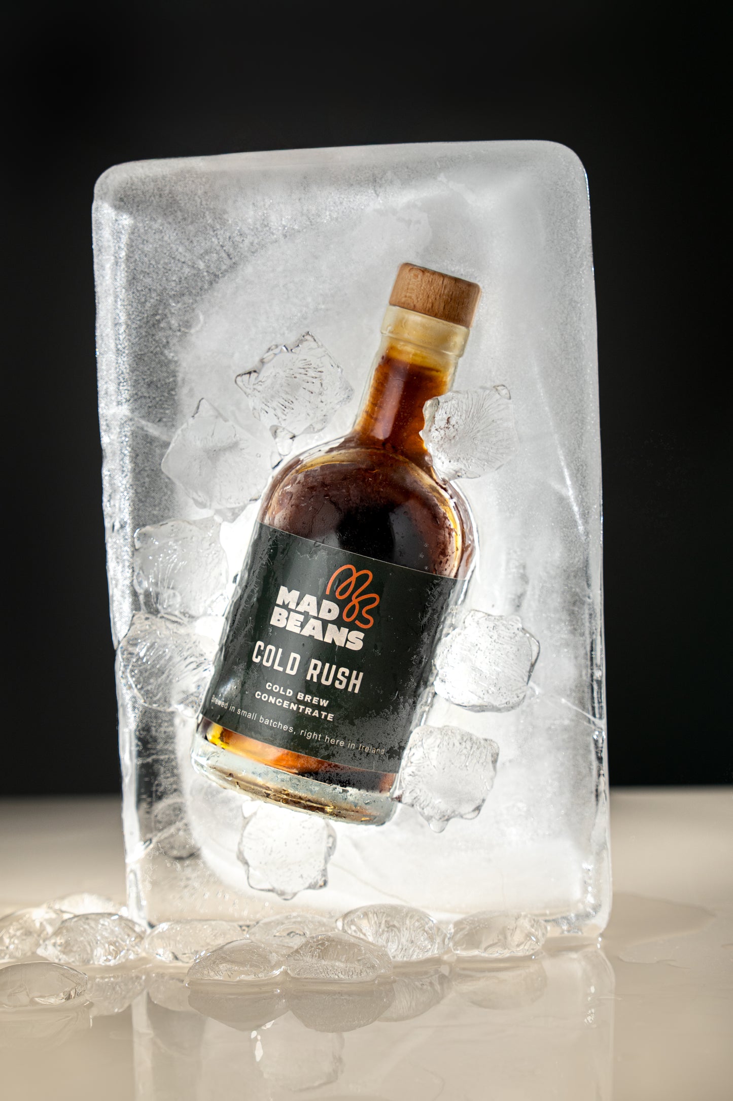Bottle of Mad Beans Cold Rush in a block of ice against a dark background
